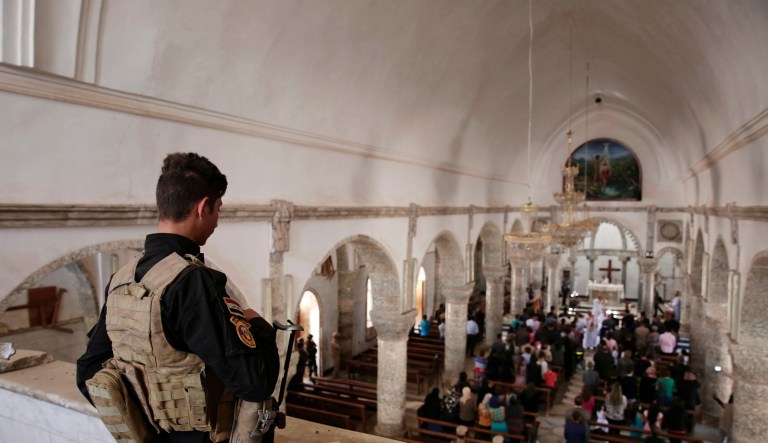 In this April 16, 2017, photo a Christian militiaman stands guard during Easter mass in Qaraqosh, Iraq.