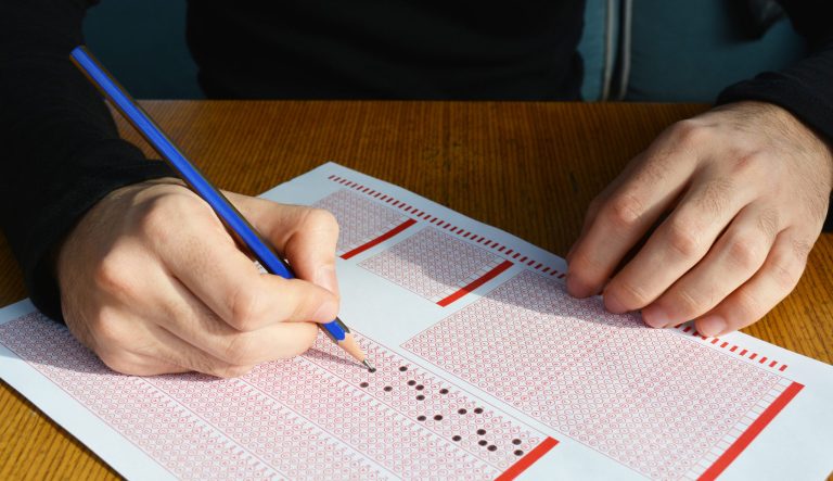 A boy filling out answers on an exam answer sheet.
