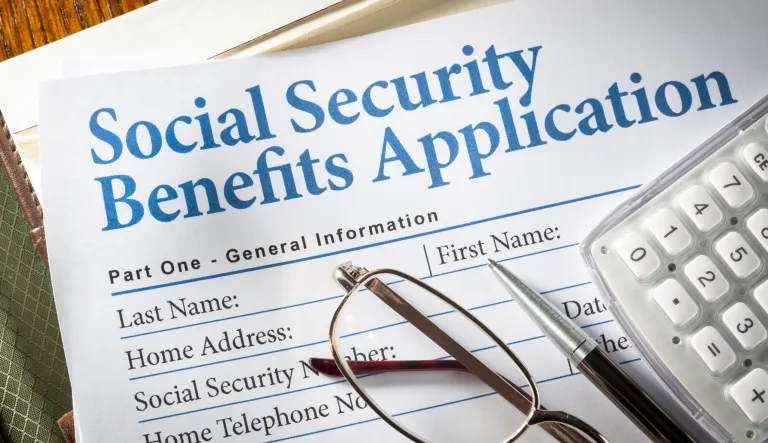 Social Security Benefits form with pen, glasses, and calculator.