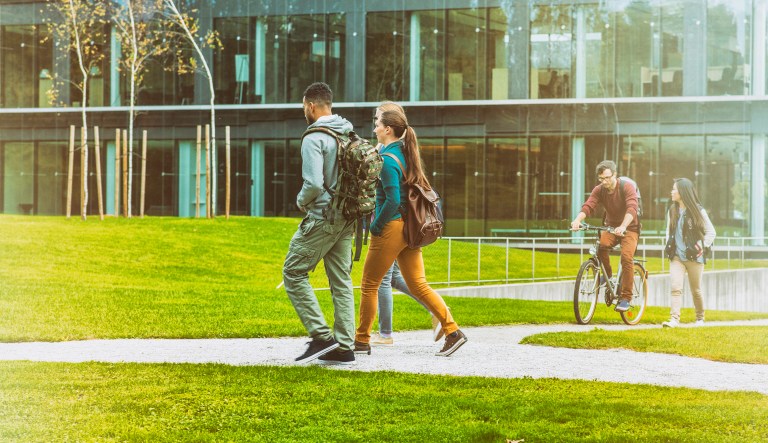 Students move through the park in in front of a university building.