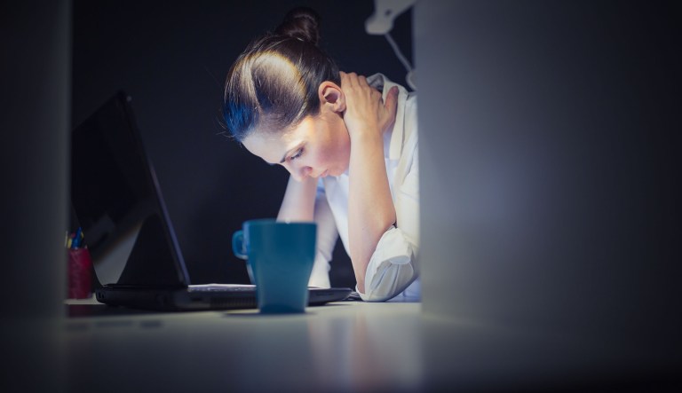 A stressed woman is seen at work during the evening.
