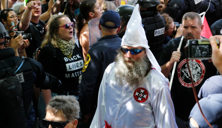 This July 8, 2017, photo shows members of the KKK escorted by police past a large group of protesters during a KKK rally in Charlottesville, Va.