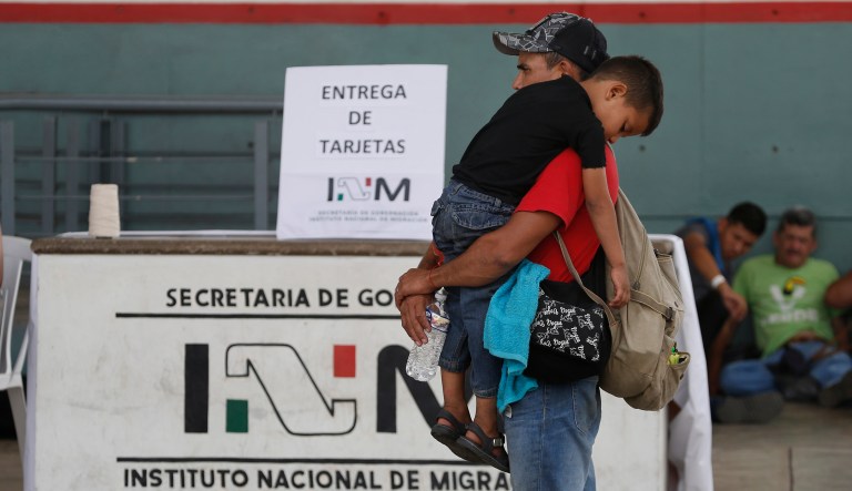 A Central American migrant carries a child as he waits for his humanitarian visa from Mexican migration officials to be processed, on the border between Mexico and Guatemala, near Ciudad Hidalgo, Chiapas state, Mexico, Sunday, Jan. 20, 2019.