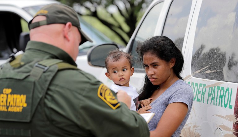 In this Monday, June 25, 2018 file photo, a mother migrating from Honduras holds her 1-year-old child as surrendering to U.S. Border Patrol agents after illegally crossing the border, near McAllen, Texas.