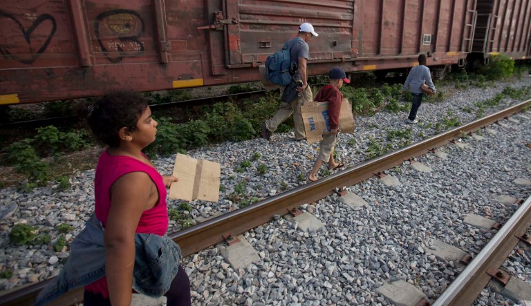 In this July 12, 2014, photo, migrants walk along the rail tracks after getting off a train during their journey toward the U.S.-Mexico border in Ixtepec, Mexico.