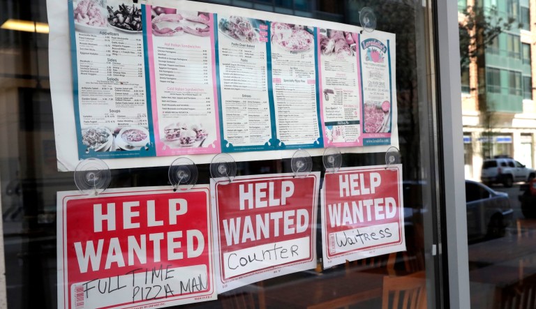Help wanted signs hang below menus at a restaurant in the Newport section of Jersey City, N.J., on May 2, 2018.