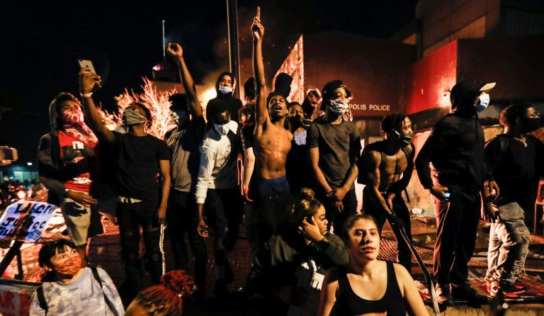 Protestors demonstrate outside of a burning Minneapolis 3rd Police Precinct, Thursday, May 28, 2020, in Minneapolis. Protests over the death of George Floyd, a black man who died in police custody Monday, broke out in Minneapolis for a third straight night.