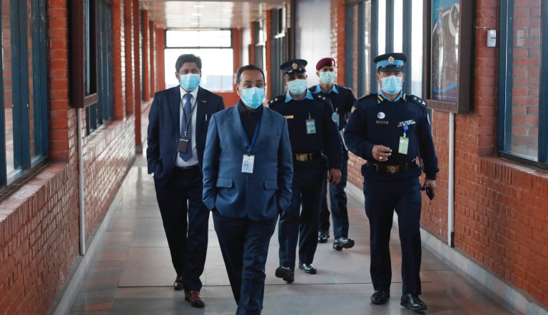Nepalese government officers and policemen wearing face masks walk at Tribhuwan International airport in Kathmandu, Nepal, Tuesday, Jan. 28, 2020. Authorities have started screening passengers after one confirmed case of a new coronavirus infection was detected in the Himalayan country.