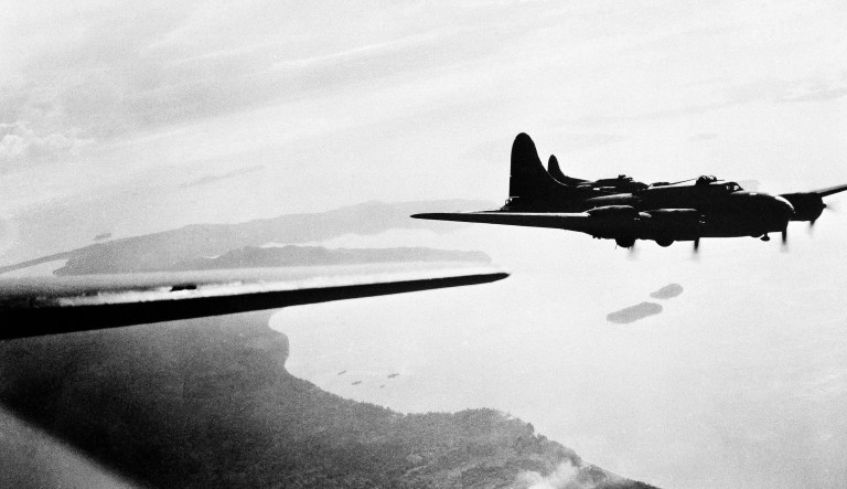 A flight of American Flying Fortress planes sails over the Japanese strong air base of Kahili on the island of Bougainville in the Northern Solomons, Oct. 11, 1943.  Ships beside coast are in ship's anchorage.  Tonoleie Harbor is in center, directly between wings of planes. This airfield is target repeatedly for Yank forces on bombing missions. 