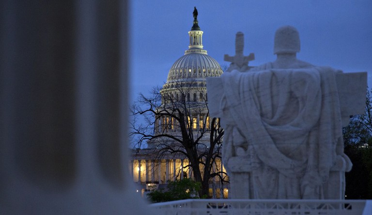The U.S. Capitol building stands past the "Authority of Law" statue at the U.S. Supreme Court building in Washington, D.C., U.S., on Friday, April 7, 2017. Judge Neil Gorsuch is poised to win an intensely political confirmation fight to join a Supreme Court already struggling to stay above politics. The Senate's expected confirmation of Gorsuch Friday will restore the generally conservative majority that existed before Justice Antonin Scalia's death last year.