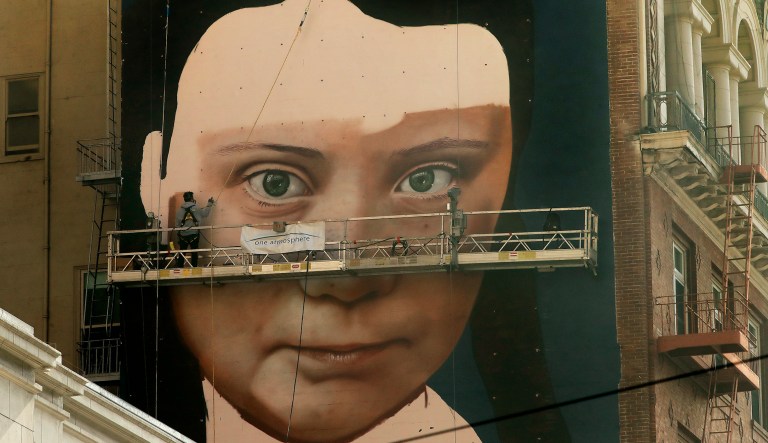 Andres Petreselli paints a mural on the side of a building depicting Swedish teen climate activist Greta Thunberg, Friday, Nov. 8, 2019, in San Francisco.