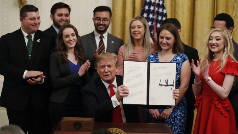 President Donald Trump holds up an executive order requiring colleges to certify that their policies support free speech as a condition of receiving federal research grants, after signing, Thursday March 21, 2019, in the East Room of the White House in Washington. 