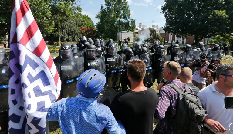 FILE - In this Aug. 12, 2017, file photo, white nationalist demonstrators hold their ground against Virginia State Police as police fire tear gas rounds in Lee Park in Charlottesville, Va. A federal judge is set to hear arguments Thursday, May 24, 2018, from white nationalists and others that a lawsuit against them over last summerâs violence in Charlottesville should be dismissed.