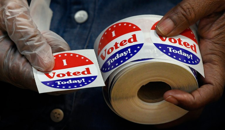 A volunteer holds a sticker to give to a voter.