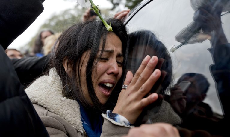 A woman touches the funeral car transporting the remains of Argentine rock star Gustavo Cerati at the cemetery in Buenos Aires, Argentina, Friday, Sept. 5, 2014. Cerati died on Thursday, four years after a stroke put him in a coma and ended the career of one of Latin America's most influential musicians.  (AP Photo/Natacha Pisarenko)