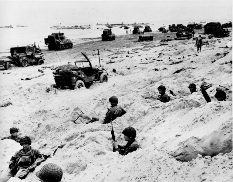 This June 6, 1944, file photo shows American soldiers of the Allied Expeditionary Force securing a beachhead during initial landing operations at Normandy, France, June 6, 1944.  From the first sketchy German radio broadcast to the distribution of images filmed in color, it has taken decades for the full story of the D-Day invasion to come out. As world leaders and veterans prepare to mark the 70th anniversary of the invasion this week, multiple Twitter hashtags are following the ceremonies minute by minute. At the time, the reporting, filming and taking of photos was neither easy nor straightforward. (AP Photo/Weston Haynes, File)