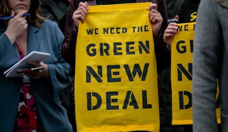 A supporter holds a flag endorsing the Green New Deal, Feb. 7, 2019, outside the Capitol.