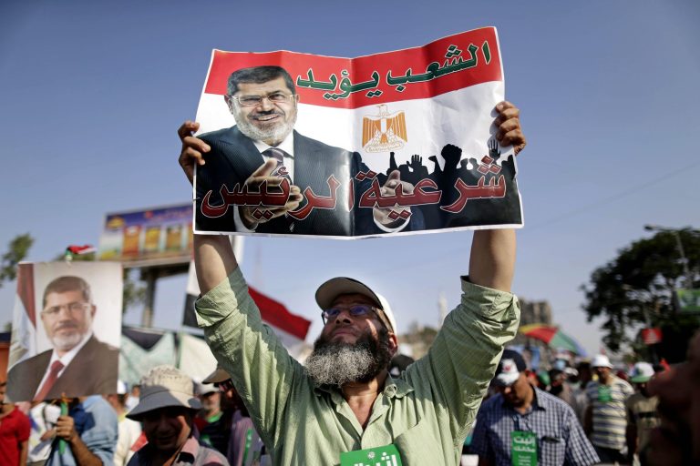 A supporter of Egypt's Islamist President Mohammed Morsi holds a poster with Arabic that reads, 