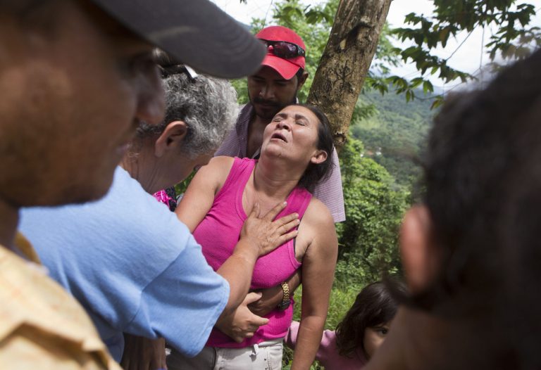 Margarita Mendez is helped by friends while she waits for news her son Salvador Urbina, one of the miners trapped at El Comal gold and silver mine after a landslide trapped at least 24 miners inside, in Bonanza, Nicaragua, Friday, Aug. 29, 2014. Rescuers on Friday located 20 of at least 24 gold miners trapped by a landslide in northern Nicaragua, but were not immediately able to bring them to safety. (AP Photo/Esteban Felix)