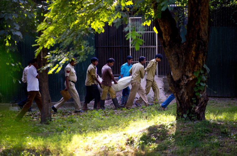 Workers carry the body of a man who was killed by a white tiger past its cage at the zoo in New Delhi, India, Tuesday, Sept. 23, 2014. The white tiger killed the man who climbed over a fence and jumped into the animal's enclosure Tuesday, a spokesman said. (AP Photo/Saurabh Das)