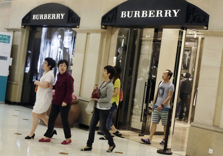   Shoppers exit a Burberry shop Wednesday, June 13, 2012, in Shanghai, China. Chinese consumers can afford to splash out more on higher quality products, but also expect better value for money than in the past, according to a study by the American Chamber of Commerce. (AP Photo/Eugene Hoshiko)  