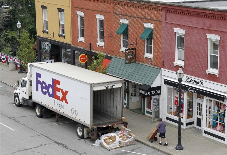   FILE - In this Wednesday, May 23, 2012, file photo, A Federal Express truck makes a delivery in downtown Chagrin Falls, Ohio. FedEx said Tuesday, Dec. 4, 2012, that it will be offering some employees up to two years' pay to leave the company starting next year. The voluntary program is part of an effort by the world's second-biggest package delivery company to cut annual costs by $1.7 billion within three years. (AP Photo/Amy Sancetta, File)  