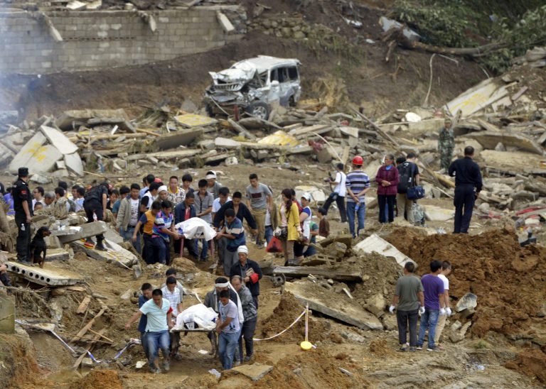 In this Thursday Aug. 28, 2014 photo, residents remove bodies in the aftermath of a landslide at Yingping village in Fuquan city in southwest China's Guizhou province. Hundreds of rescuers hunted Friday for survivors of a massive landslide in southwestern China that killed at least a dozen people. (AP Photo) CHINA OUT