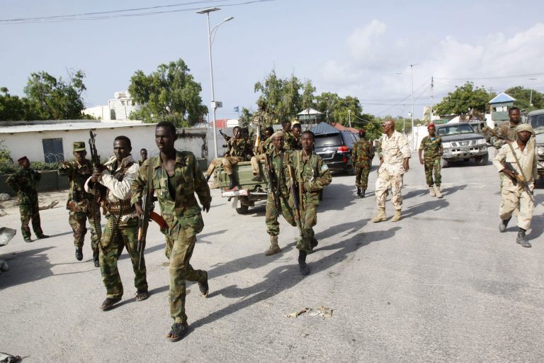 Somali soldiers patrol near the wreckage of a car bomb that was detonated at the main gate of the presidential palace in Mogadishu, Somalia, Wednesday, July, 9, 2014. Somali troops retook the presidential palace in the capital of Mogadishu after militants forced their way in and exchanged heavy gunfire with troops and guards Tuesday, the latest attack underscoring the threat posed by Islamic extremist group al-Shabab in east Africa.  (AP Photo/Farah Abdi Warsameh)