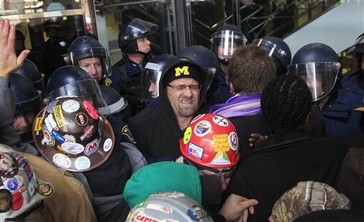 Michigan State Police push the crowd back outside the George W. Romney Office Building in Lansing, Mich., Tuesday, Dec. 11, 2012. Thousands of protesters rallied outside the state Capitol as lawmakers pushed final versions of right-to-work legislation. The GOP majority has used its superior numbers and backing from Gov. Rick Snyder to speed the legislation through the House and Senate last week, brushing aside denunciations and walkouts by helpless Democrats and cries of outrage from union activists who swarmed the state Capitol hallways and grounds. (AP Photo/Carlos Osorio)
