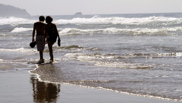 FILE - In this Aug. 26, 2010 file photo, a couple walks through the surf together in Cannon Beach, Ore. OKCupid on Monday, July 28, 2014 became the latest company to admit that it has manipulated customer data to see how users of its dating service would react to one another. (AP Photo/Don Ryan, File)