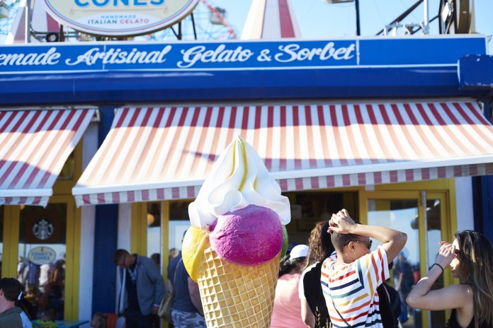 Pedestrians pass an ice cream shop on the Coney Island boardwalk in early July. Consumer spending is buoying the U.S. economy, though analysts worry that President Trump's trade conflicts may hurt growth later in the year. 