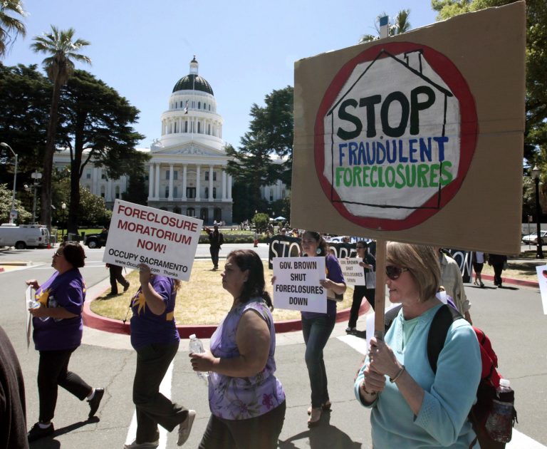 Demonstrators march past the state Capitol during a protest on home foreclosures in Sacramento, Calif.,  Monday, June 25, 2012.  About 100 protestors gathered at the state Capitol and marched to two different banks, demanding that the governor, attorney general and lawmakers declare an immediate moratorium on home foreclosures in the state. (AP Photo/Rich Pedroncelli)
