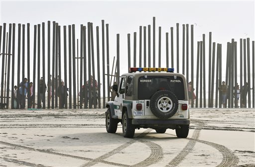 ADVANCE FOR USE MONDAY, FEB. 25, 2013 AND THEREAFTER - FILE - In this Jan. 18, 2009 file photo, a U.S. Border Patrol vehicle sits parked in front of a crowd of people peering through the U.S.-Mexico border fence at Border Field State Park in San Diego. At one time, before the enhanced border fence in the area, the San Diego area held the most popular routes for illegal immigrants heading into the U.S. (AP Photo/Denis Poroy)