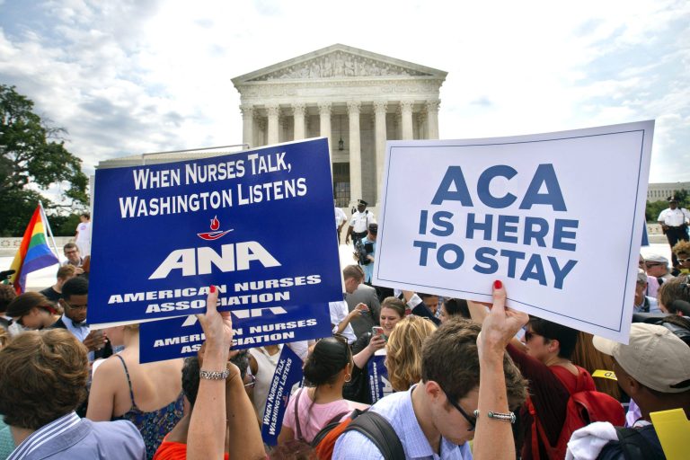Supporters of the Affordable Care Act hold up signs as the opinion for health care is reported outside of the Supreme Court in Washington, Thursday June 25, 2015. (AP Photo)