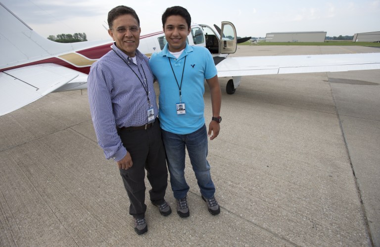 File - In this June 19, 2014 file photo, Babar Suleman, left, and son Haris Suleman, 17, stand next to their plane at an airport in Greenwood, Ind., before taking off for an around-the-world flight. Officials in American Samoa on Monday, Aug. 4, 2014, recovered a personal locator beacon registered to the Sulemans, who crashed off the U.S. territory last month as they attempted to fly around the world. Haris Suleman died in the July 22 crash and his father, Babar Suleman, remains missing. (AP Photo/The Indianapolis Star, Robert Scheer, File)