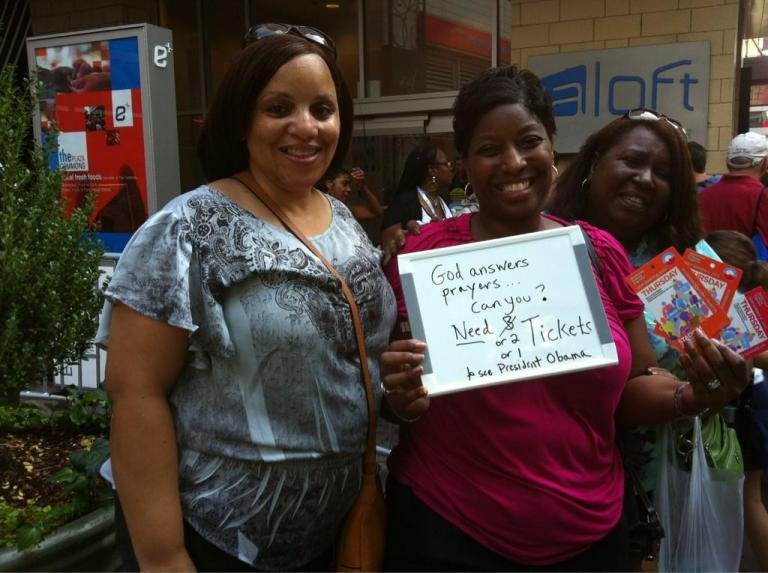 Women from D.C. hold up a sign asking for tickets to hear Obama speak in the Time Warner Cable Arena (Brian Hughes/Examiner)