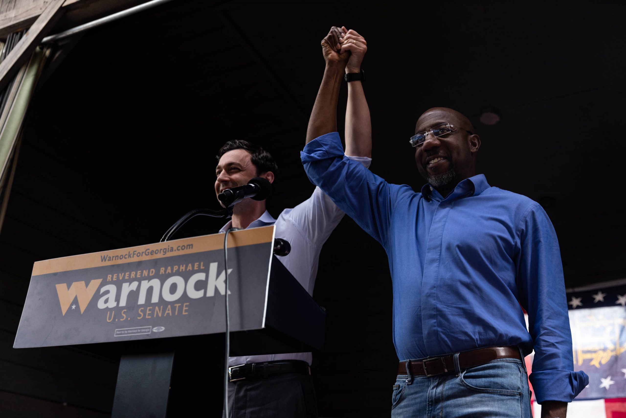 Sen. Jon Ossoff joins hands with Sen. Raphael Warnock at a campaign rally in Macon, Georgia, Monday, November, 7, 2022