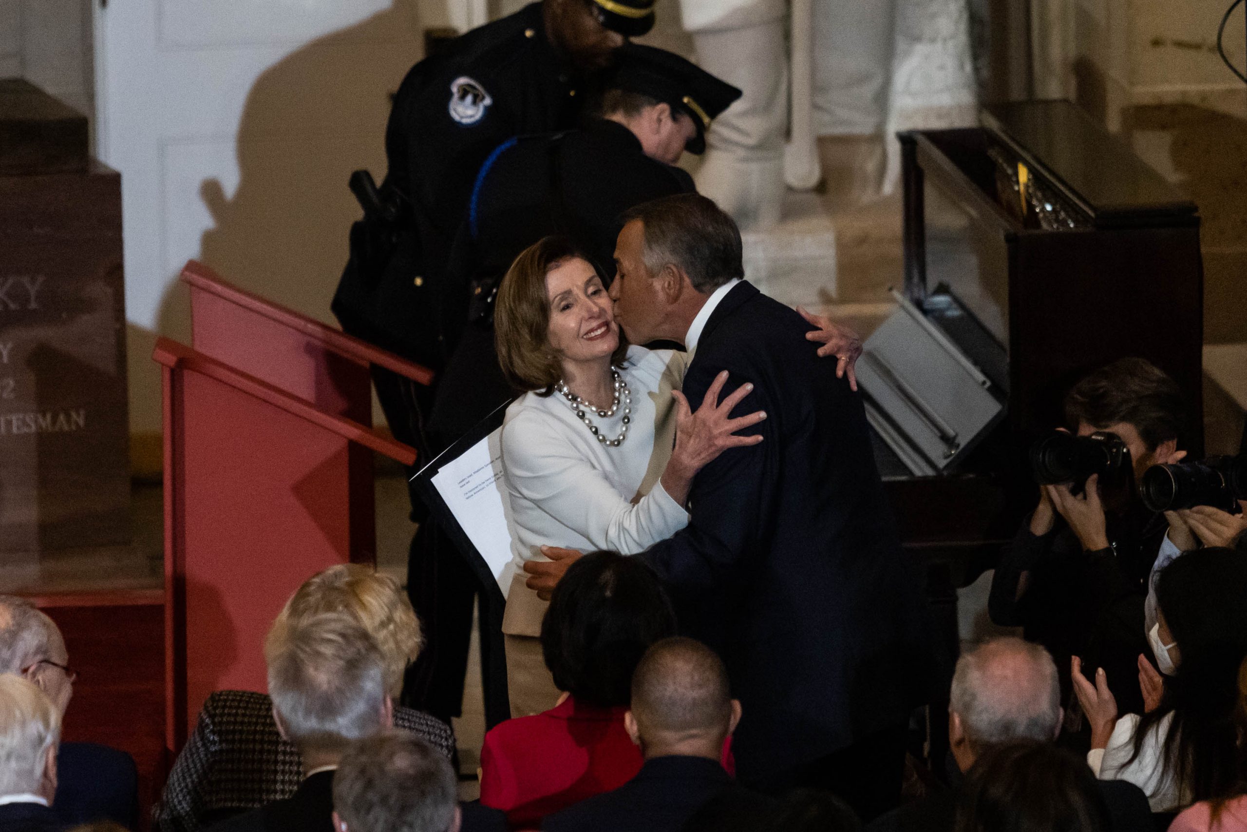 House Speaker Nancy Pelosi receives a kiss from former House Speaker John Boehner during the unveiling of her official portrait in Statuary Hall at the U.S. Capitol December, 14, 2022.