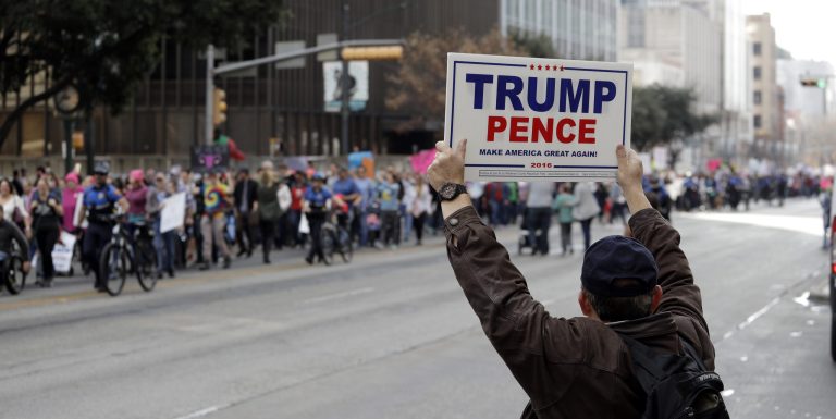America divided. A supporter of President Donald Trump holds a sign as a women's march heading to the Texas State Capitol passes on the one-year anniversary of President Donald Trump's inauguration, Saturday, Jan. 20, 2018, in Austin, Texas. (AP Photo/Eric Gay)