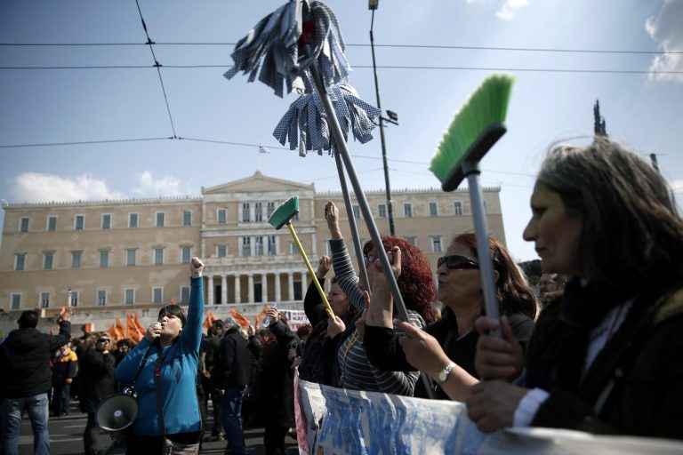 FILE - In this Wednesday, March 12, 2014 file photo, protesting cleaning staff fired by the Finance Ministry march holding up buckets and mops during a rally outside the Greek parliament in central Athens. The workers won a class-action case against the government, with a court declaring their dismissal illegal, according to a May 12, 2014 court decision made public Friday May 16. (AP Photo/Petros Giannakouris, File)