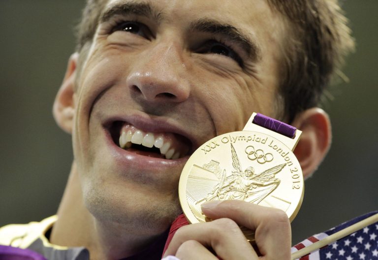 Michael Phelps poses with his gold medal for the men's 4x200-meter freestyle relay in London in 2012. If the Rio de Janeiro Olympics were held today, the United States would win the most medals and the most gold medals. And American swimmer Michael Phelps would collect five more gold medals and a bronze, bringing his overall total to 28 with a career gold-medal haul to 23. (AP Photo/Matt Slocum, File)