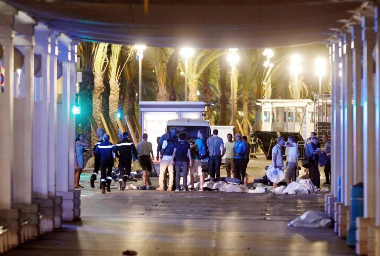 People stand next to covered bodies in the early hours of Friday, July 15, 2016, on the Promenade des Anglais in Nice, southern France. France has been stunned again as a large white truck killed many people after it mowed through a crowd of revelers gathered for a Bastille Day fireworks display late Thursday evening, in the Riviera city of Nice. (AP Photo)