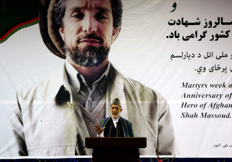 Afghan President Hamid Karzai, speaks during a for a ceremony honoring the late Commander Ahmad Shah Massoud, background, a beloved anti-Taliban fighter who was assassinated 13 years ago, in Kabul, Afghanistan, Tuesday, Sept. 9, 2014.  Karzai urged the country's two presidential candidates to reach an agreement on a new national unity government at the state function that devolved into raucous shouting by agitated supporters of candidate Abdullah Abdullah. Karzai told the crowd of hundreds of powerbrokers to urge Abdullah and Ashraf Ghani Ahmadzai to reach a deal to end the country's now five-month-long election process. (AP Photo/Rahmat Gul)