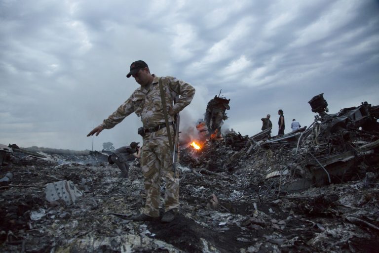People walk amongst the debris at the crash site of a passenger plane near the village of Grabovo, Ukraine, Thursday, July 17, 2014. Ukraine said a passenger plane carrying 295 people was shot down Thursday as it flew over the country, and both the government and the pro-Russia separatists fighting in the region denied any responsibility for downing the plane. (AP Photo/Dmitry Lovetsky)