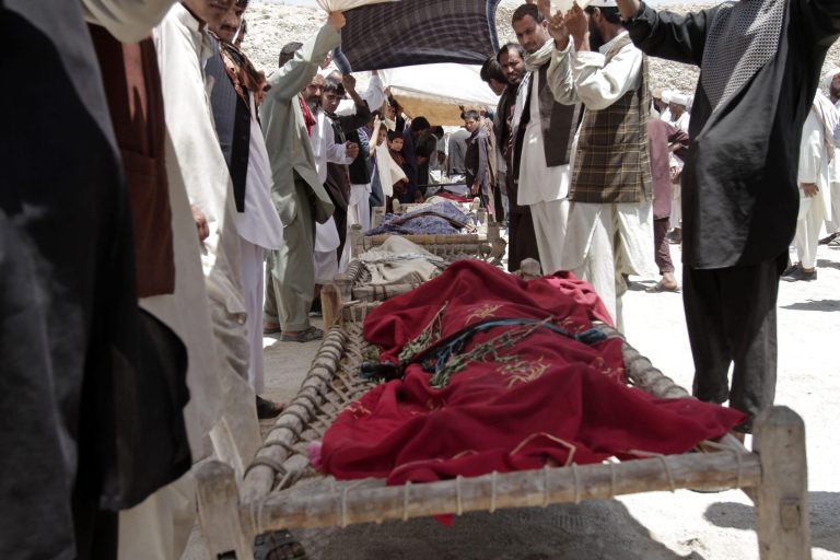 Afghan men provide shade to the bodies of 7 civilians killed, after their vehicle was hit by a road side bomb, during funeral preparations in the Alingar district of Laghman province, east of Kabul, Afghanistan, Monday, June 03, 2013. A statement from the provincial government said a group of four women and two children had gone with a male driver into the hills to collect firewood. On their way back, their vehicle hit the mine and all inside were killed. (AP Photo/Rahmat Gul)
