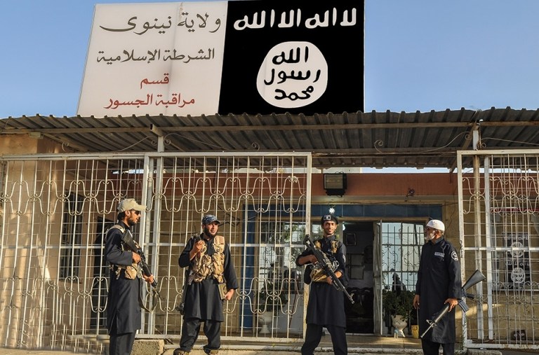 This undated image posted on a militant website on Friday, Sept. 19, 2014, which has been verified and is consistent with other AP reporting, shows Islamic State group policemen standing guard in front of a police station in Nineveh province, Iraq. Arabic reads, 
