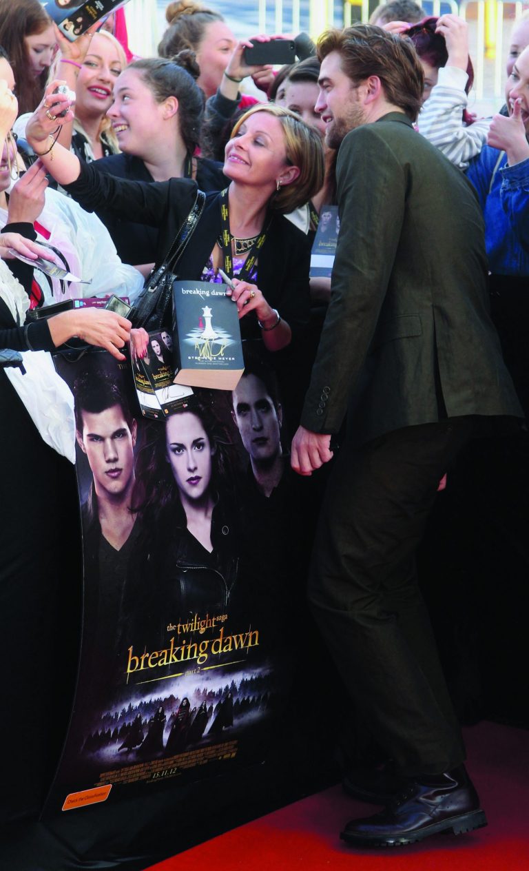 FILE - This Oct. 22, 2012 file photo shows British actor Robert Pattinson, right, having his photo taken with fans upon arrival for an exclusive fan event for the final chapter of the Twilight Saga 