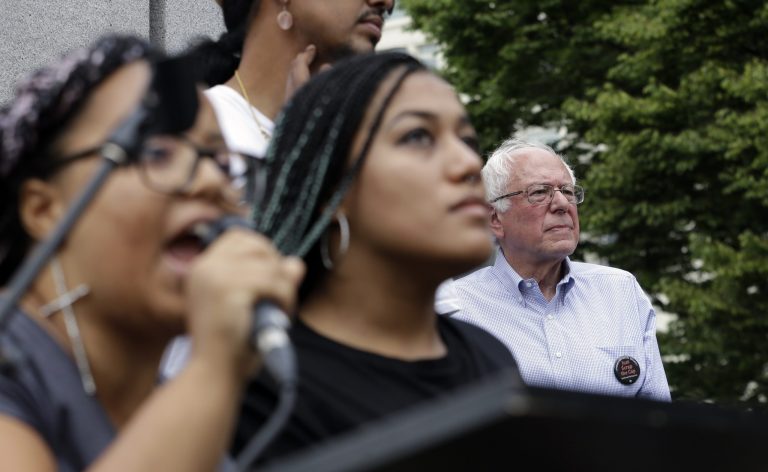 Marissa Johnson, left, and Mara Jacqueline Willaford speak as Sen. Bernie Sanders, I-Vt., stands nearby after the two women took over the microphone at a rally Saturday, Aug. 8, 2015, in downtown Seattle. (AP Photo/Elaine Thompson)