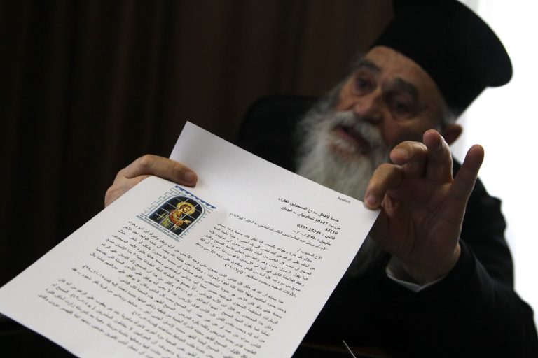 In this Sunday, Feb. 2, 2014 Father Gervasios holds up a letter, in Arabic, copies of which are handed out to all prisoners his charity frees, in their own language, explaining why they receive the help in the northern port city of Thessaloniki. The soft-spoken 83-year-old with a long white beard and black robes has helped more than 15,000 convicts secure their freedom over nearly four decades, according to records kept by his charity. The Greek rules apply only to people convicted of offences that carry a maximum five-year sentence, such as petty fraud, bodily harm, weapons possession, illegal logging, resisting arrest and minor drugs offences. (AP Photo/Nikolas Giakoumidis)