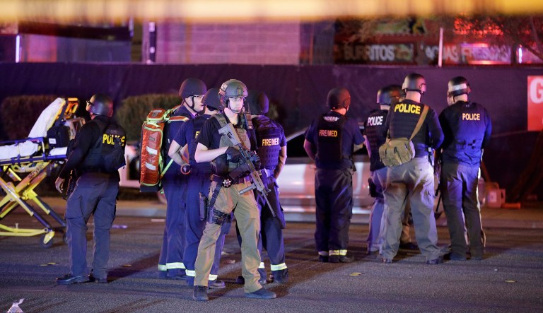 Police officers and medical personnel stand at the scene of a shooting near the Mandalay Bay resort and casino on the Las Vegas Strip. Multiple victims were being transported to hospitals after a shooting late Sunday. President Trump tweeted his condolences to those affected by the shooting at a country music concert in Las Vegas. (AP Photo/John Locher)